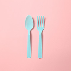 Blue plastic fork and spoon isolated on pink background