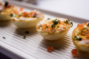 Fried hot boiled egg masala is a popular healthy breakfast or starter menu from India. With onion, coriander, black pepper, tomato and salt sprinkled over half of eggs