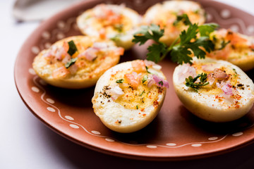 Fried hot boiled egg masala is a popular healthy breakfast or starter menu from India. With onion, coriander, black pepper, tomato and salt sprinkled over half of eggs