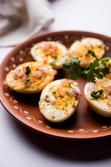 Fried hot boiled egg masala is a popular healthy breakfast or starter menu from India. With onion, coriander, black pepper, tomato and salt sprinkled over half of eggs