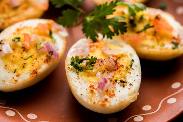 Fried hot boiled egg masala is a popular healthy breakfast or starter menu from India. With onion, coriander, black pepper, tomato and salt sprinkled over half of eggs