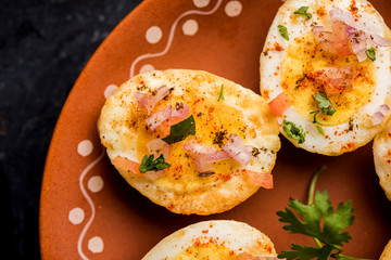 Fried hot boiled egg masala is a popular healthy breakfast or starter menu from India. With onion, coriander, black pepper, tomato and salt sprinkled over half of eggs