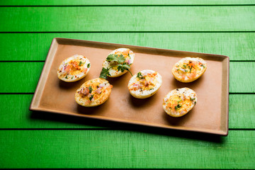 Fried hot boiled egg masala is a popular healthy breakfast or starter menu from India. With onion, coriander, black pepper, tomato and salt sprinkled over half of eggs