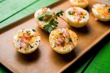 Fried hot boiled egg masala is a popular healthy breakfast or starter menu from India. With onion, coriander, black pepper, tomato and salt sprinkled over half of eggs