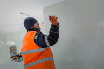 Worker covers the joints of ice panels with wet snow