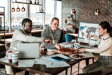 Positive delighted young people having dinner at work