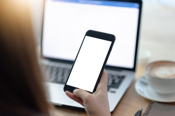 close-up on hand holding phone showing white screen on desk at coffee shop.