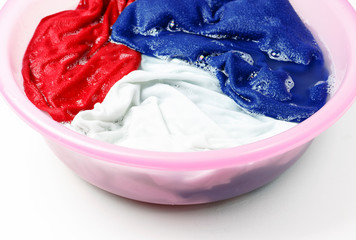 Colorful clothes washed with a basin with soap bubbles, close-up