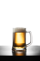 Frosty mug of light beer on wood table