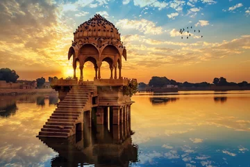 Fotobehang Oude architectuurruïnes bij Gadi Sagar (Gadisar) meer Jaipur Rajasthan bij zonsopgang met levendige humeurige lucht. © Roop Dey