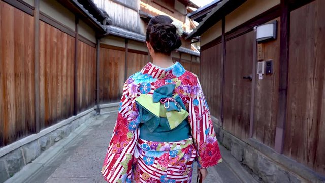 fast forward back view of geisha in floral traditional clothing in ishibe alley going to work in kyoto japan. beautiful lady in colorful kimono robe join summer festival walking in path wooden house
