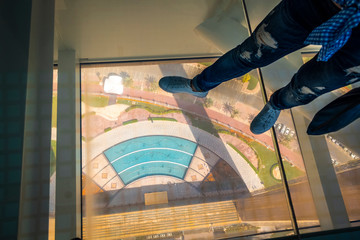 On a glass floor at high altitude in a Dubai Frame building.
