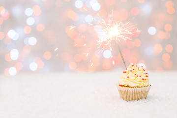 Cupcake with sparkler and fairy lights. Empty space for text