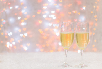 Two champagne glasses on hearts bokeh background