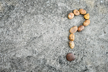 Arrange rocks question mark sign on cement floor.