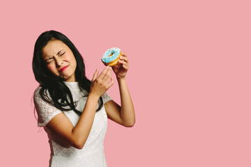 Woman holding a blue donut with a disgusted expression