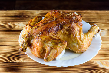 fried chicken whole, on a white plate on a wooden background