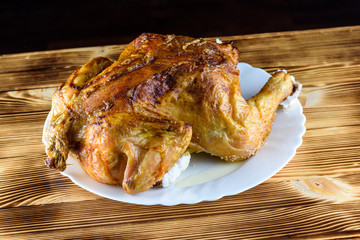 fried chicken whole, on a white plate on a wooden background