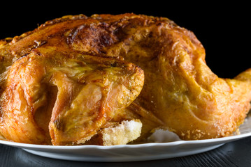 fried chicken whole, on a white plate on a wooden background