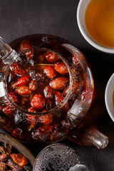 Glass teapot with vitamin rose hips. Rosehip tea. Vitamin drink on a dark background. Top view.