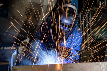 Industrial worker is welding in factory