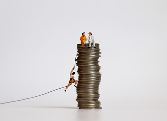 A concept of class conflict in income. Miniature people with a pile of coins.