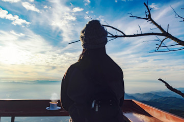 Woman traveler drinks coffee in restaurant with a view of the mountain landscape.