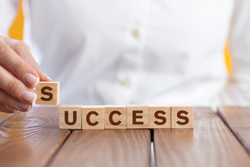 Woman hand arranging wooden cubes with word 