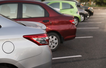 Fototapeta premium Closeup of rear or back side of bronze car with other cars parking in parking area in the evening. 