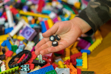 Close up of colorful plastic bricks on the floor. Early learning. Children's plastic constructor on the floor. Children's hands play a little constructor.