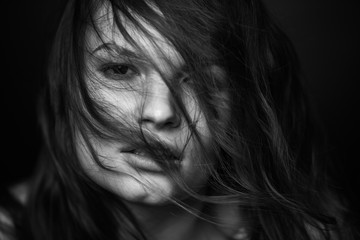 Fototapeta premium Dramatic black and white portrait of a beautiful girl on a dark background