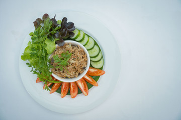 Pork chili in a white dish with cucumbers and tomatoes