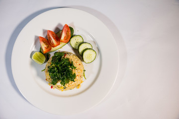 Fried rice, eggs, cucumbers and tomatoes, decorated in a white dish on a white background
