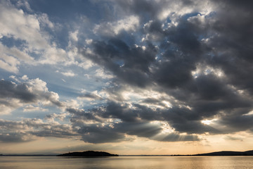 Beautiful wide angle view of a lake with an huge sky with clouds at sunset above an island