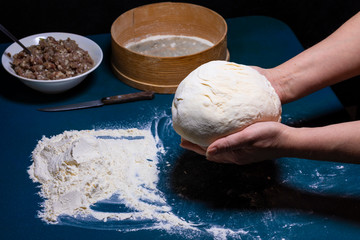 Female hands hold the dough over the table.