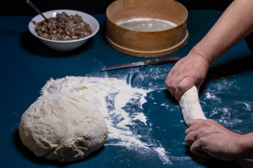 Women's hands roll out the dough.