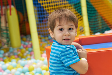 Fototapeta na wymiar child of three years old is playing in a ball pool. boy smiling spends fun time in the children's room