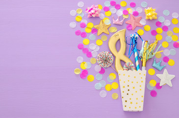 carnival party celebration concept with mask and colorful party accessories over pink wooden background. Top view.