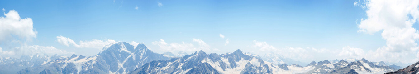 mountains peaks in the snow and clouds panoramic view