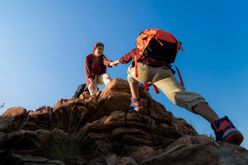 Hikers walking with backpack on a mountain at sunset. traveler going camping. travel concept.