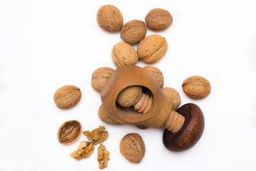 Wooden tool for crashing different nuts with several Greek nuts on white background