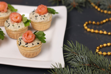Tartlets with avocado paste and salted salmon on a white plate