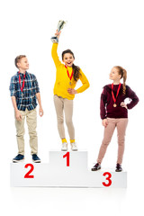 schoolchildren with medals standing on winner podium and looking at smiling schoolgirl holding...