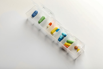 Plastic container with different pills on white background