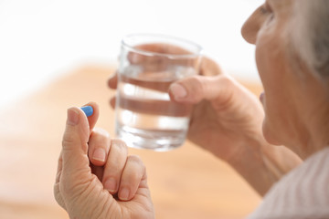 Elderly woman taking pill, closeup