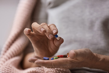 Elderly woman taking different pills, closeup