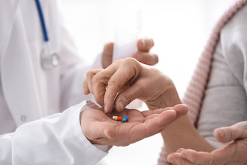 Doctor giving pills to elderly woman, closeup
