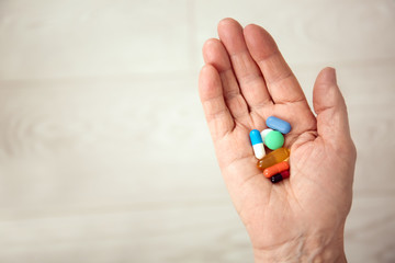 Elderly woman holding different pills on blurred background