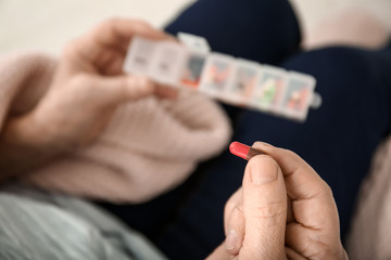 Elderly woman holding container with different pills, closeup