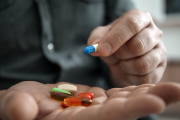 Mature man holding different pills, closeup